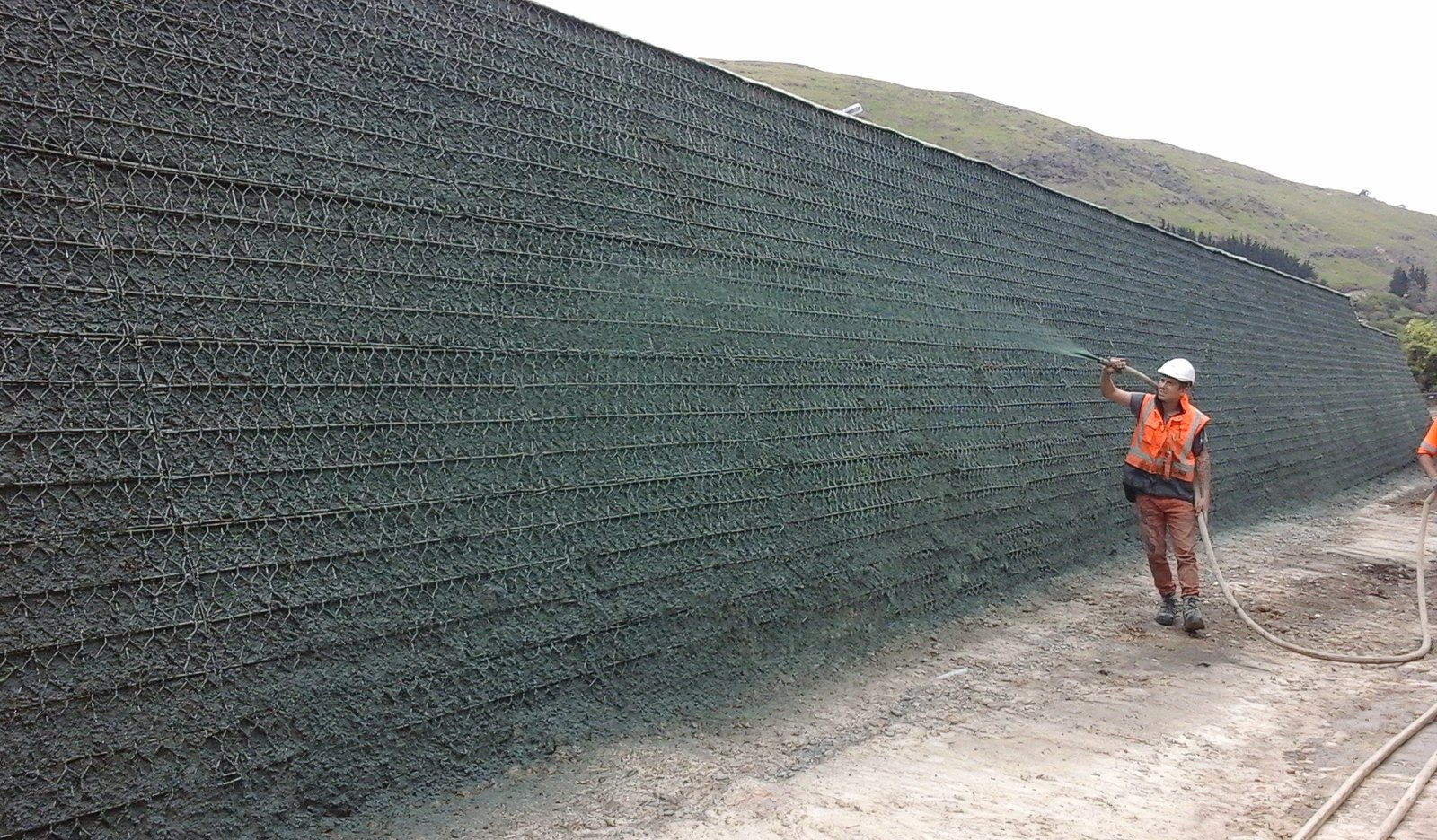 Evergreen Landcare crew applying hydraulically applied growth medium to a large mechanically stabilised earth wall